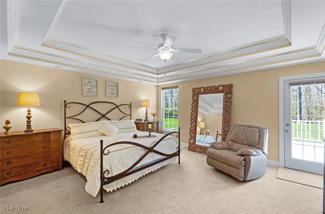 Bedroom featuring a raised ceiling, access to exterior, carpet, and ornamental molding