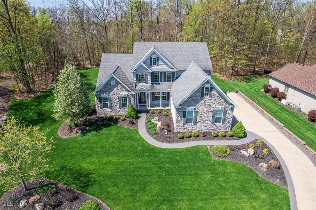 Craftsman-style house featuring stone siding, covered porch, a front yard, and driveway