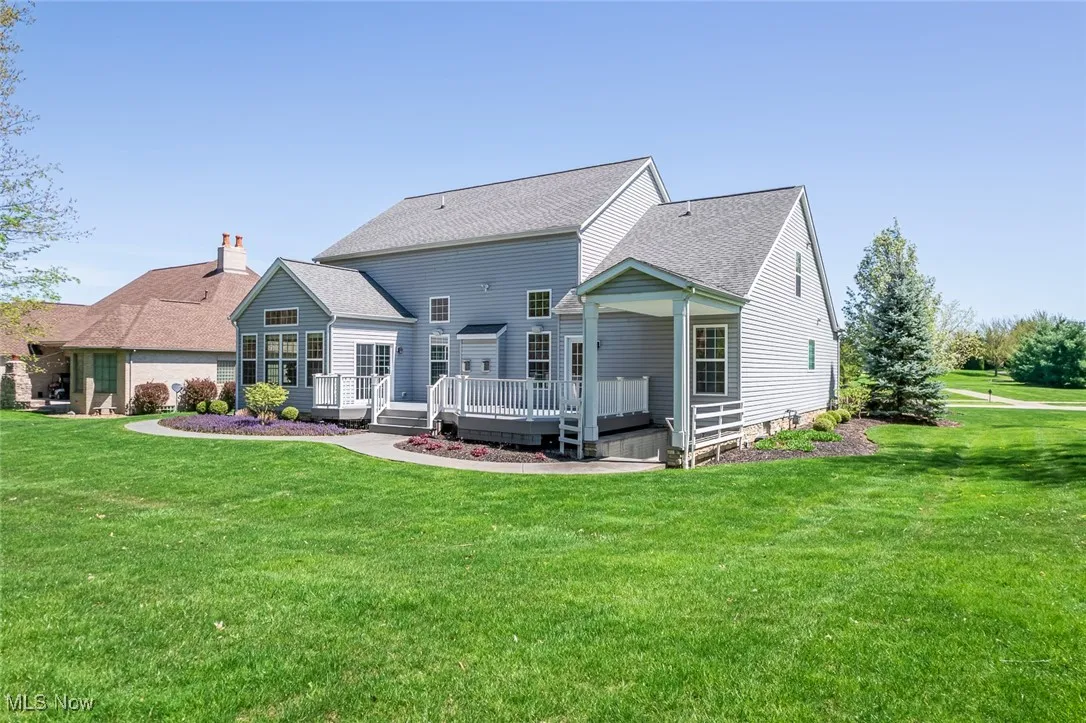 Back of property featuring a lawn, a deck, a shingled roof, and a chimney