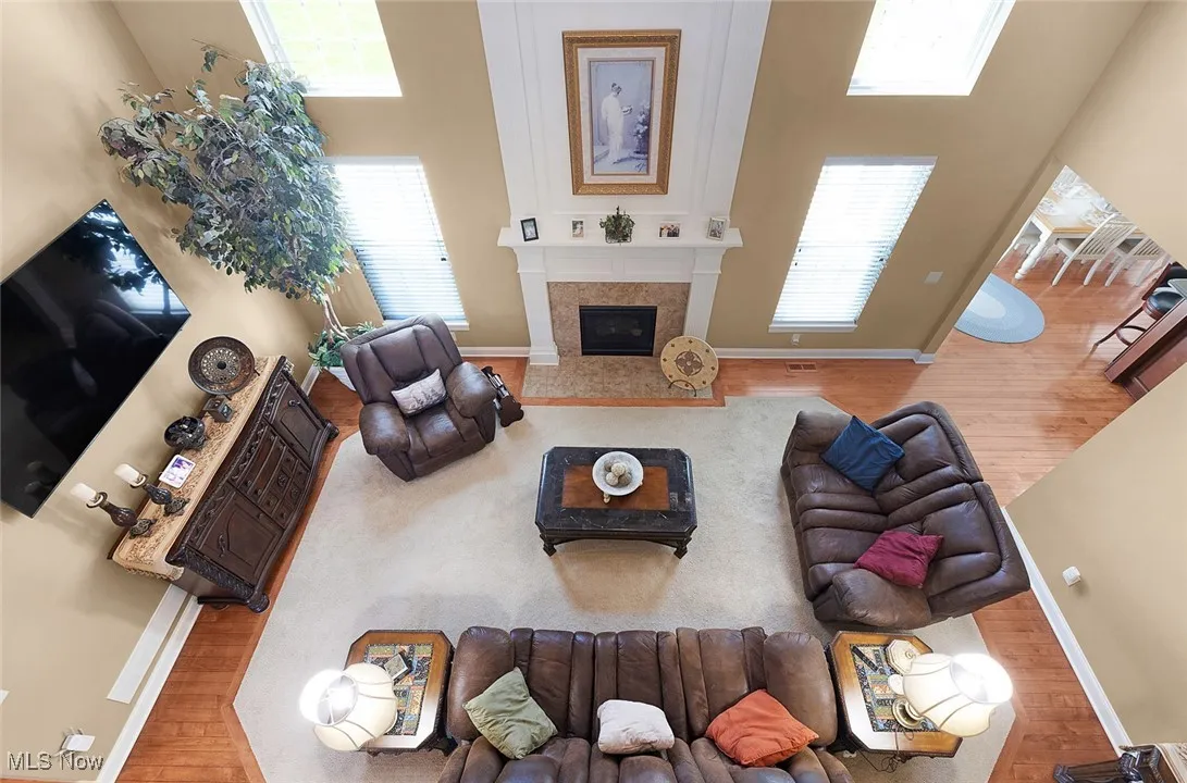 Living room featuring wood finished floors, baseboards, a high ceiling, and a glass covered fireplace