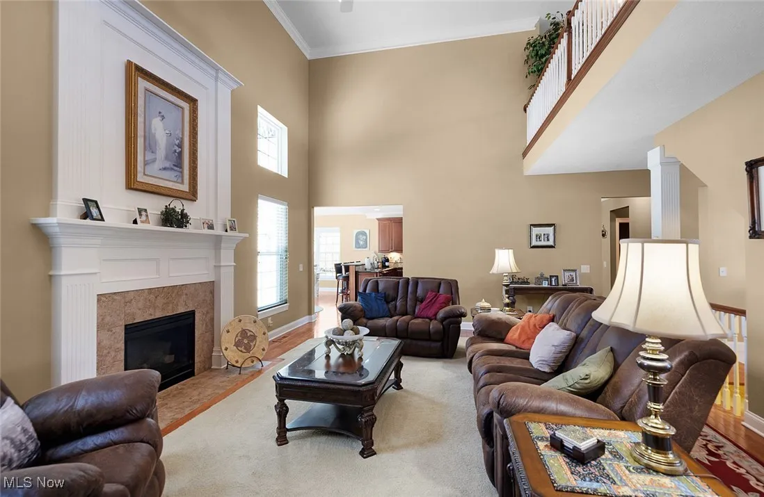 Living room with a tiled fireplace, ornamental molding, baseboards, and a towering ceiling