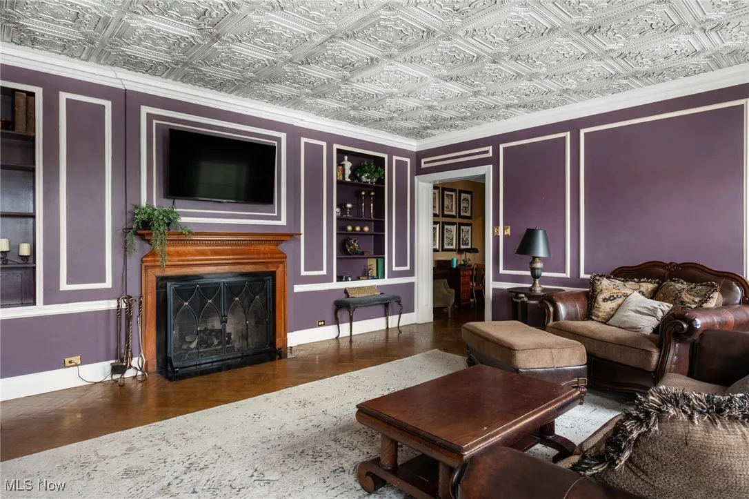 Living area with baseboards, an ornate ceiling, a fireplace, and built in features