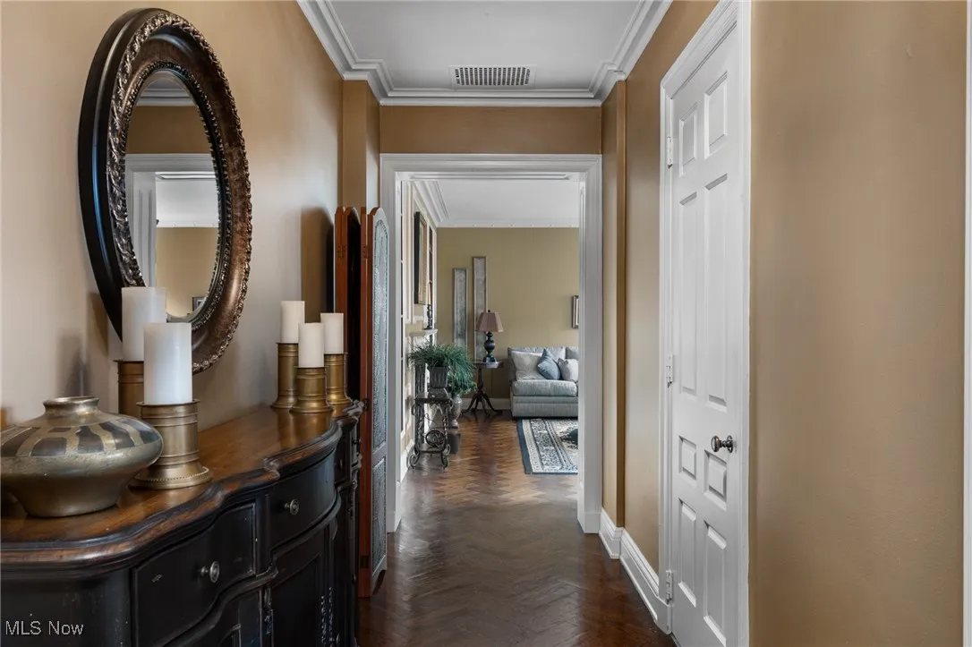 Hallway featuring ornamental molding, attic access, baseboards, and visible vents