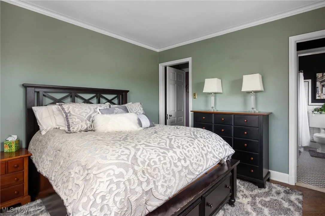 Bedroom with baseboards, connected bathroom, and crown molding