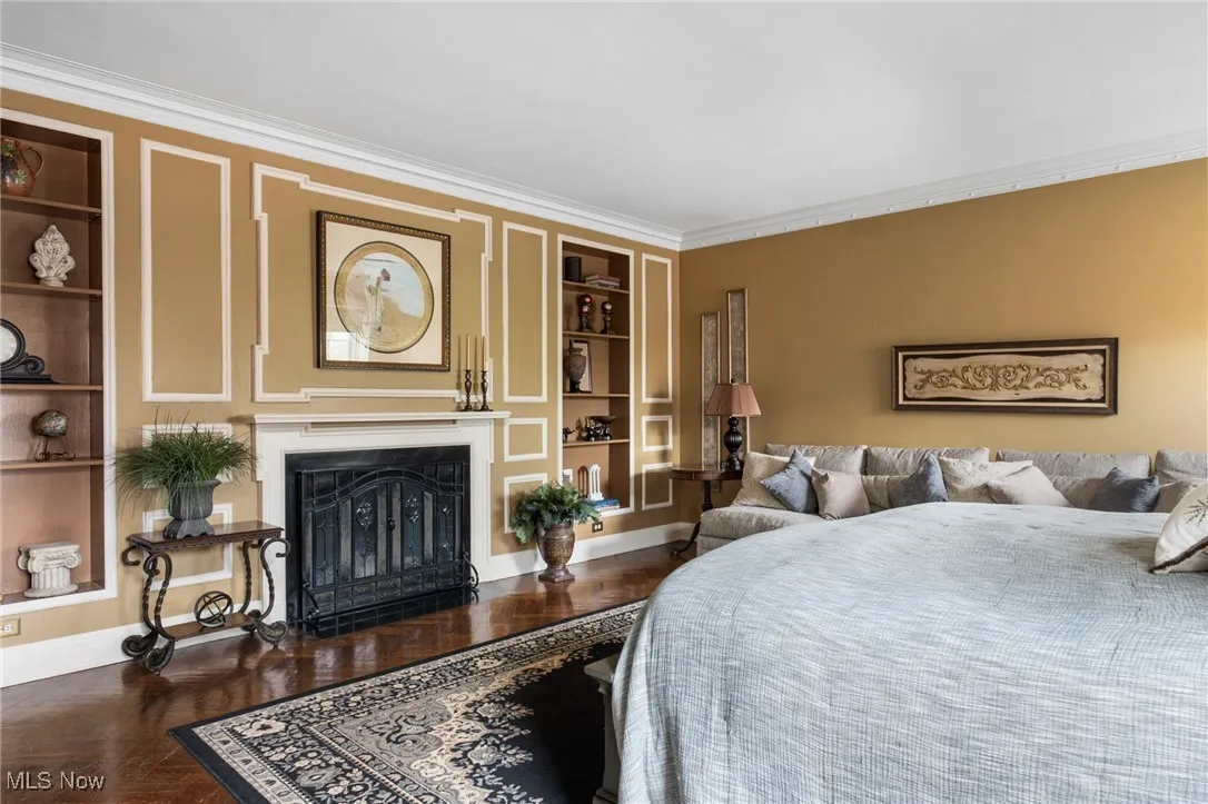 Bedroom featuring baseboards, ornamental molding, and a fireplace with flush hearth