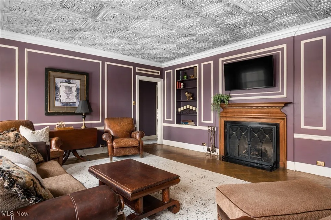 Living area featuring baseboards, an ornate ceiling, a fireplace, and built in shelves