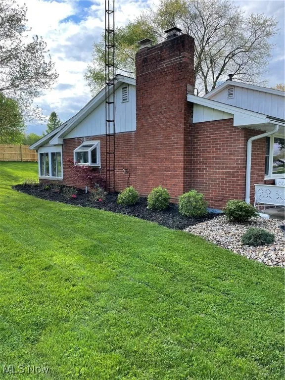 View of side of property featuring brick siding, a chimney, and board and batten siding