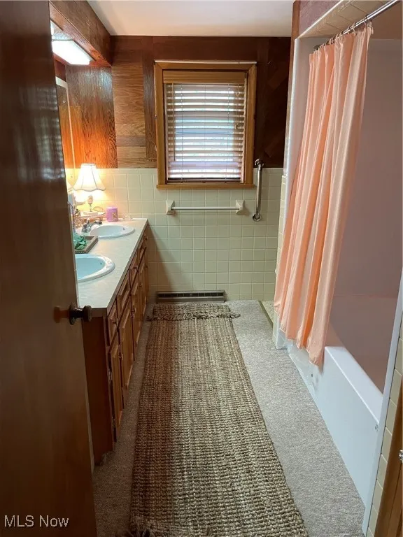 Bathroom featuring double vanity and tile walls