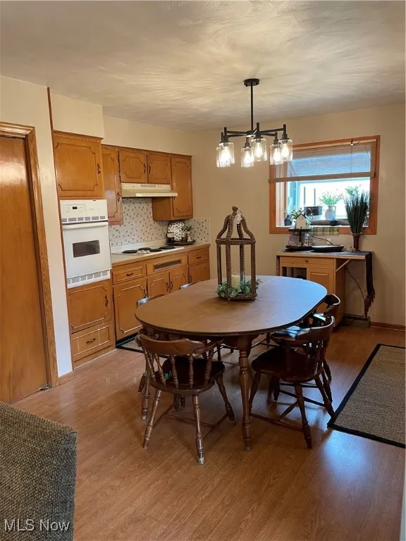 Dining area featuring light wood-type flooring, a chandelier, and baseboards
