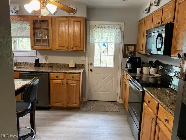 Kitchen featuring black appliances, light wood-style flooring, and brown cabinetry