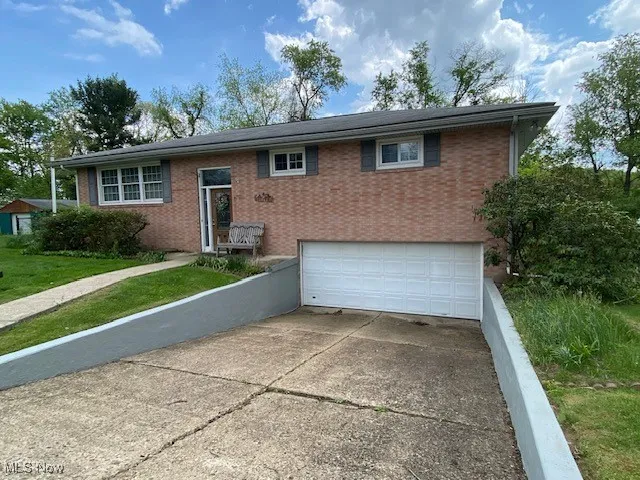 View of front facade with a garage, brick siding, concrete driveway, and a front lawn