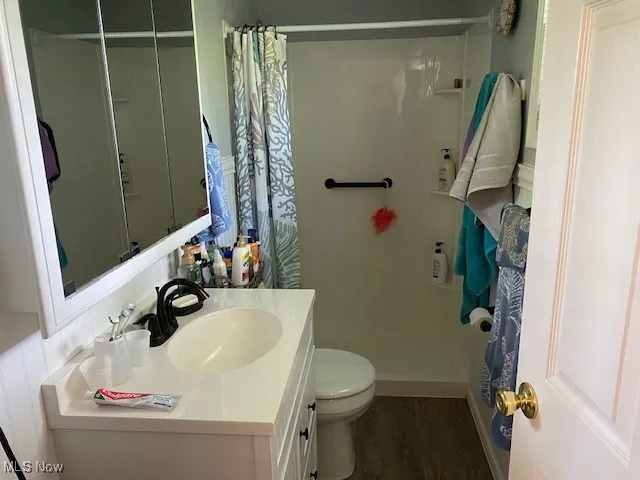 Bathroom featuring toilet, vanity, a shower with curtain, and wood finished floors