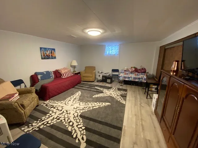 Living room with light wood-style flooring and ornamental molding