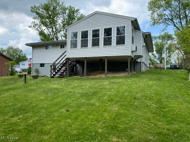 Back of property featuring stairway and a yard