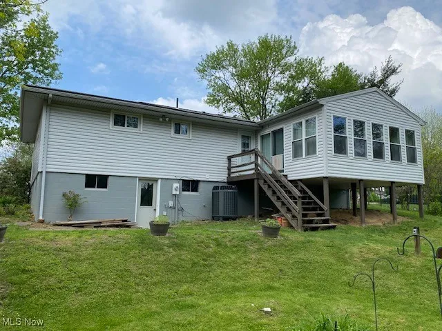 Rear view of property with central air condition unit, stairway, a yard, and a deck