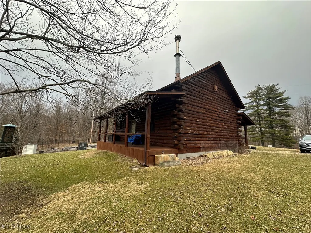 View of property exterior with log exterior, a yard, and covered porch