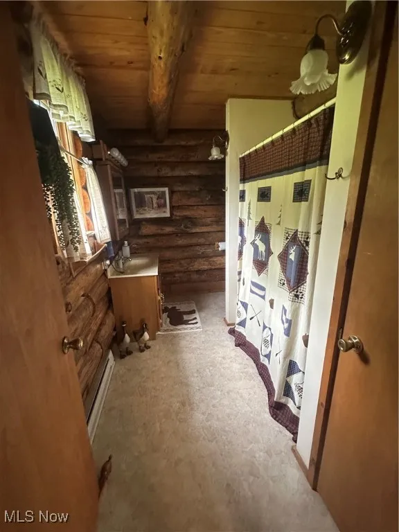 Full bath with log walls, wood ceiling, vanity, baseboard heating, and beam ceiling