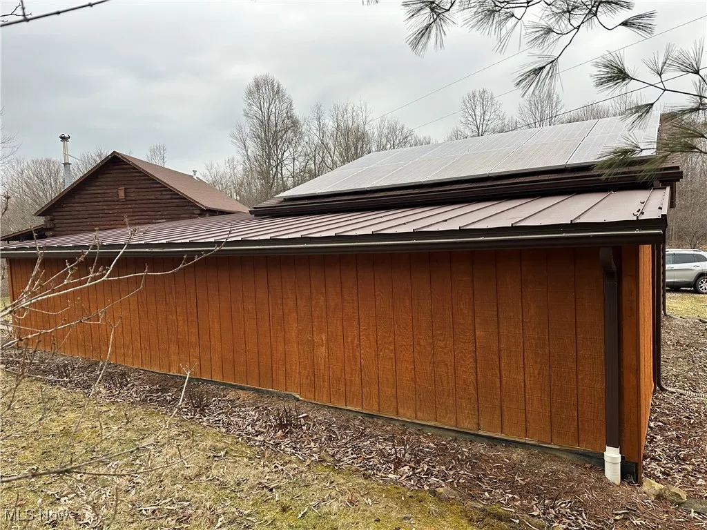 View of side of home with roof mounted solar panels and metal roof