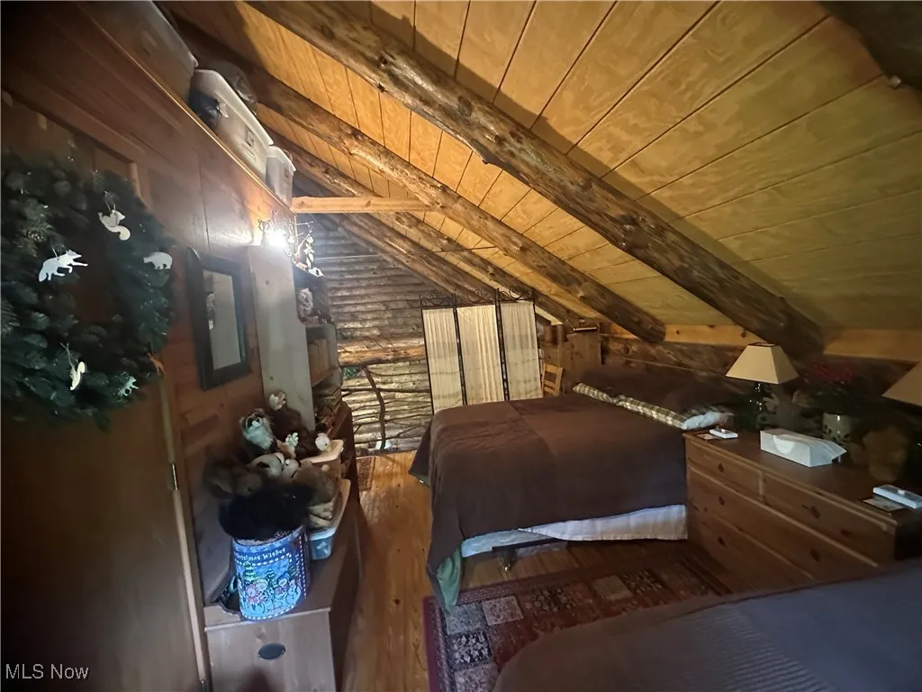 Bedroom featuring wooden ceiling, hardwood flooring, and wood walls
