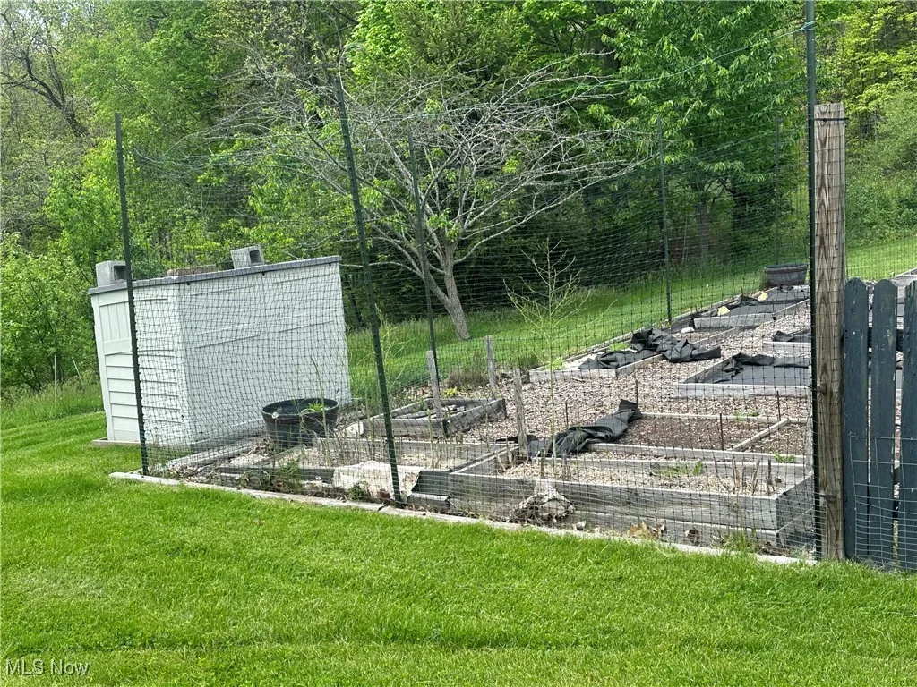 View of green lawn featuring a garden and compost bin