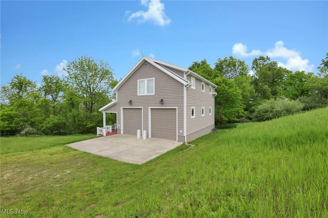 Rear view of house featuring a yard, an attached garage, and driveway