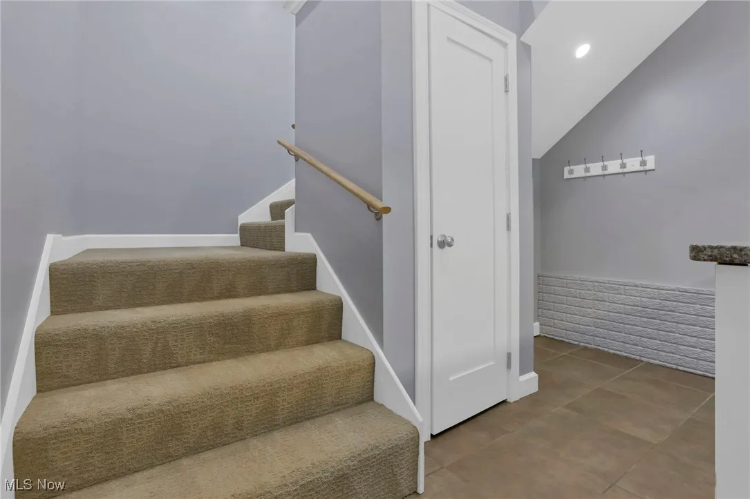 Staircase featuring lofted ceiling, baseboards, and tile patterned flooring