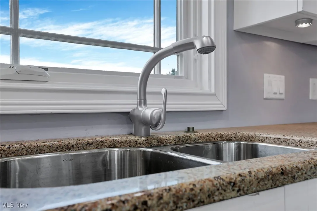 Kitchen view of a sink and light stone countertops