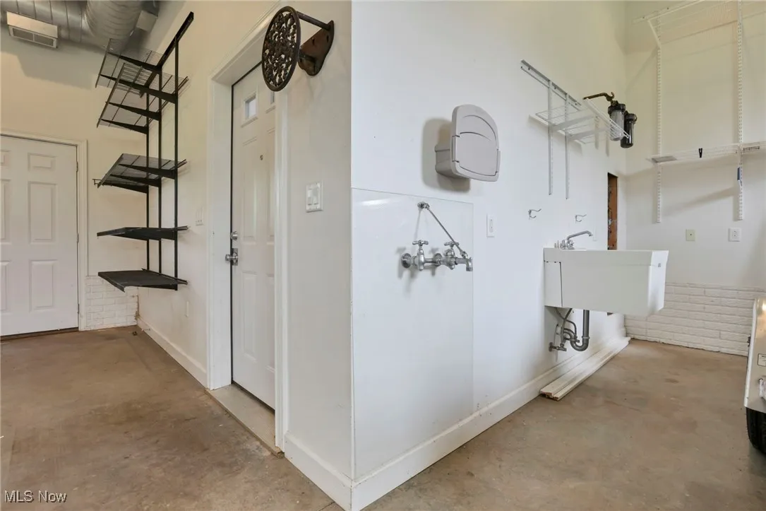 Hall featuring finished concrete flooring, baseboards, a high ceiling, and stairway