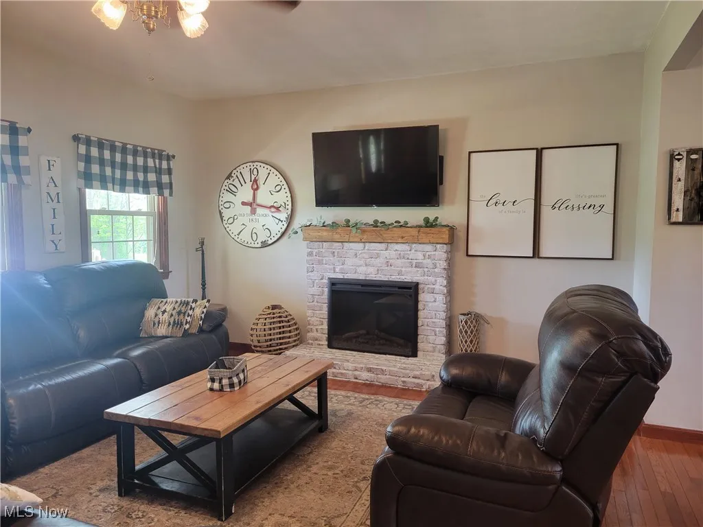 Living room featuring hardwood / wood-style floors, a brick fireplace, and ceiling fan