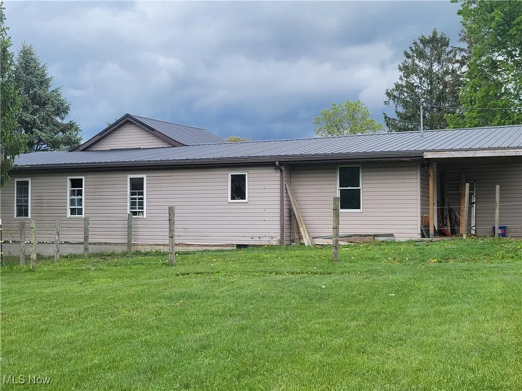 Rear view of house with a lawn and metal roof