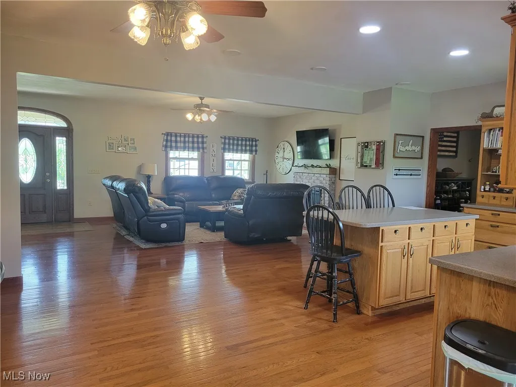 Kitchen with a ceiling fan, a breakfast bar, light wood-style flooring, light brown cabinets, and a kitchen island
