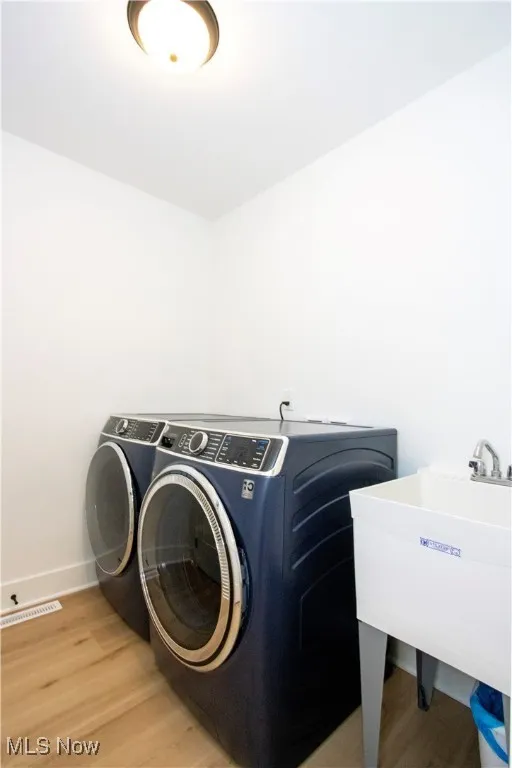 Washroom with washer and clothes dryer, light wood finished floors, and baseboards