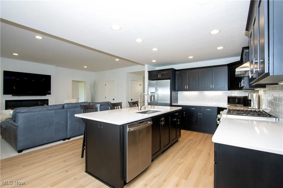 Kitchen featuring appliances with stainless steel finishes, light wood-style floors, a breakfast bar area, open floor plan, and recessed lighting