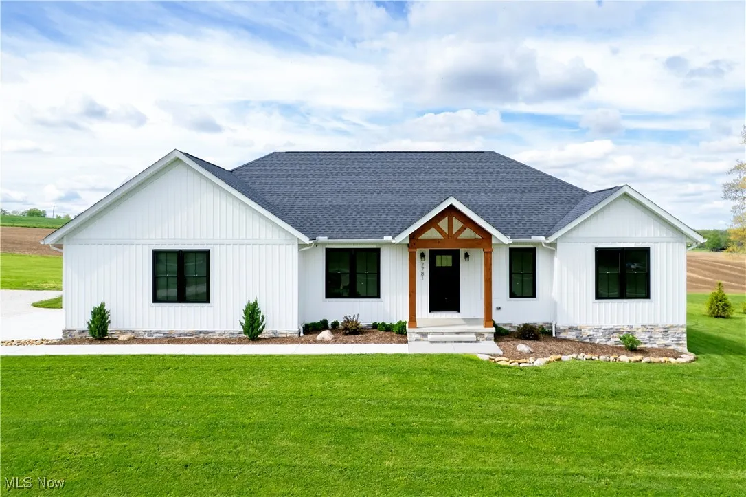 Modern farmhouse style home featuring a front yard and a shingled roof