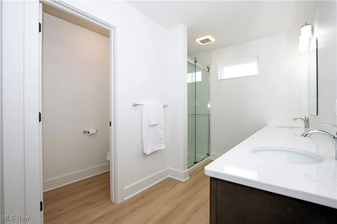 Full bath featuring wood finished floors, a shower stall, toilet, and baseboards