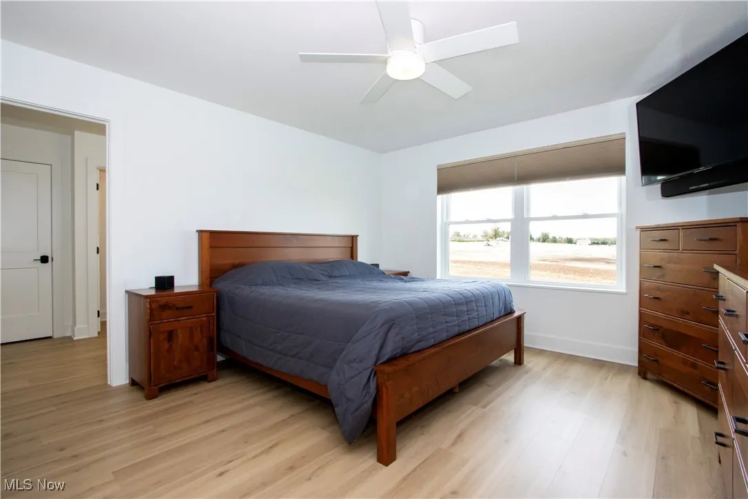 Bedroom with light wood-style flooring, a ceiling fan, and baseboards
