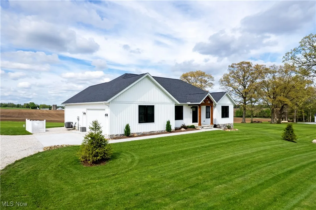 Modern farmhouse style home with concrete driveway, central air condition unit, a front yard, an attached garage, and a shingled roof