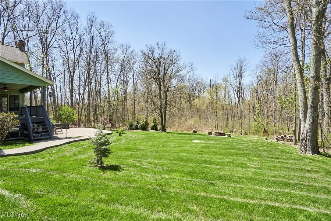 View of grassy yard featuring a ceiling fan and stairway