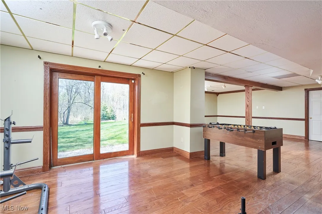 Playroom with a paneled ceiling, baseboards, and wood finished floors
