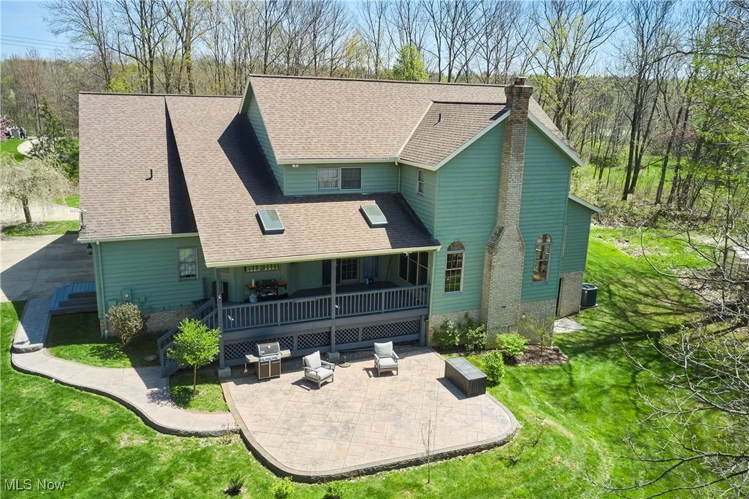 Back of house with a patio, a lawn, a chimney, a shingled roof, and central air condition unit