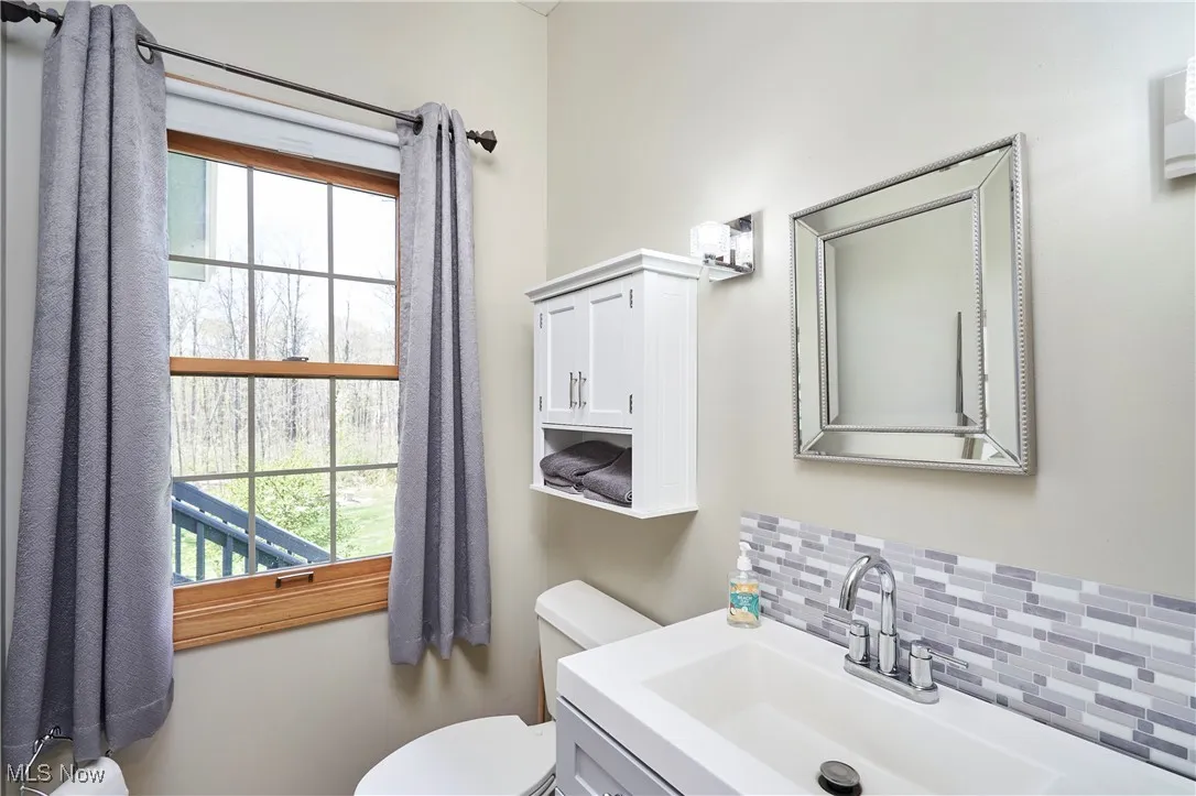 Bathroom with decorative backsplash, toilet, healthy amount of natural light, and vanity