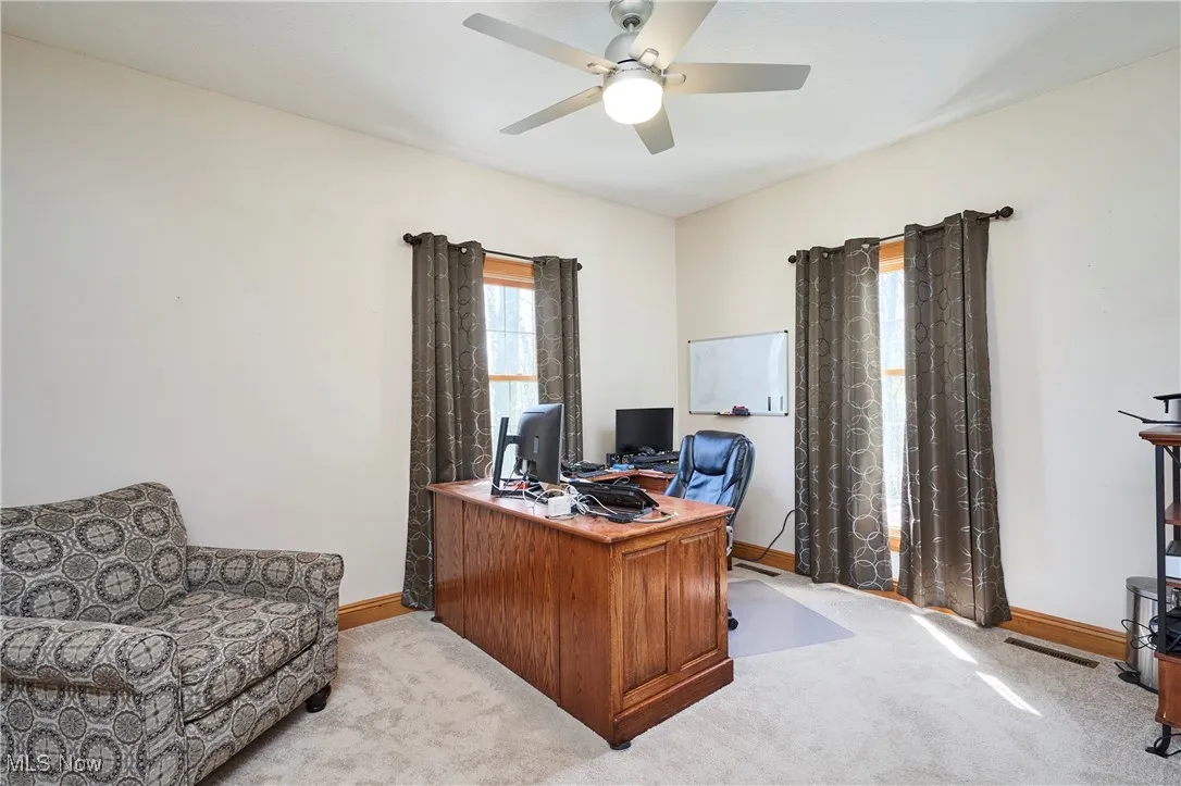 Office area with baseboards, light colored carpet, and ceiling fan