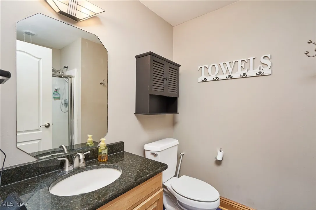 Full bath with a shower with shower door, toilet, and vanity