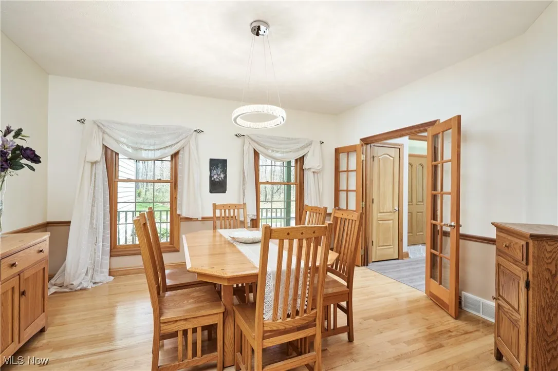 Dining space with light wood-style floors, french doors, and baseboards