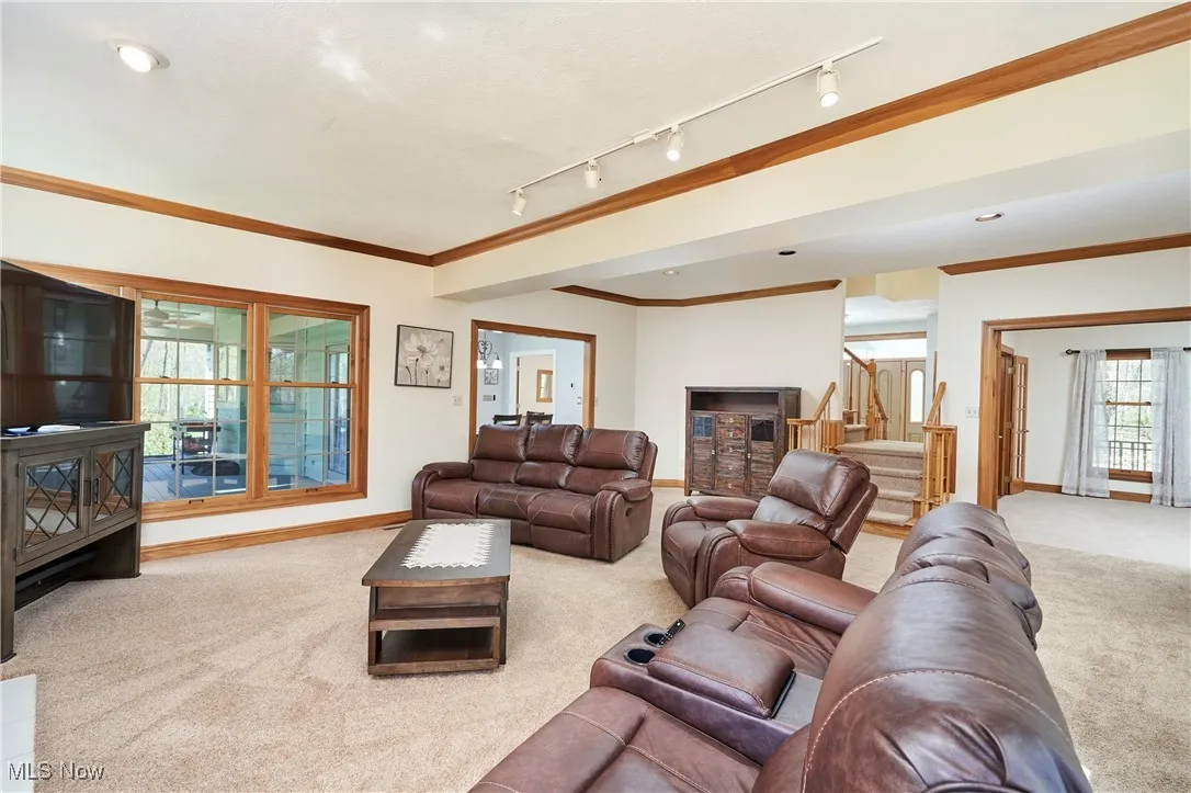 Living room with carpet floors, stairs, baseboards, and ornamental molding