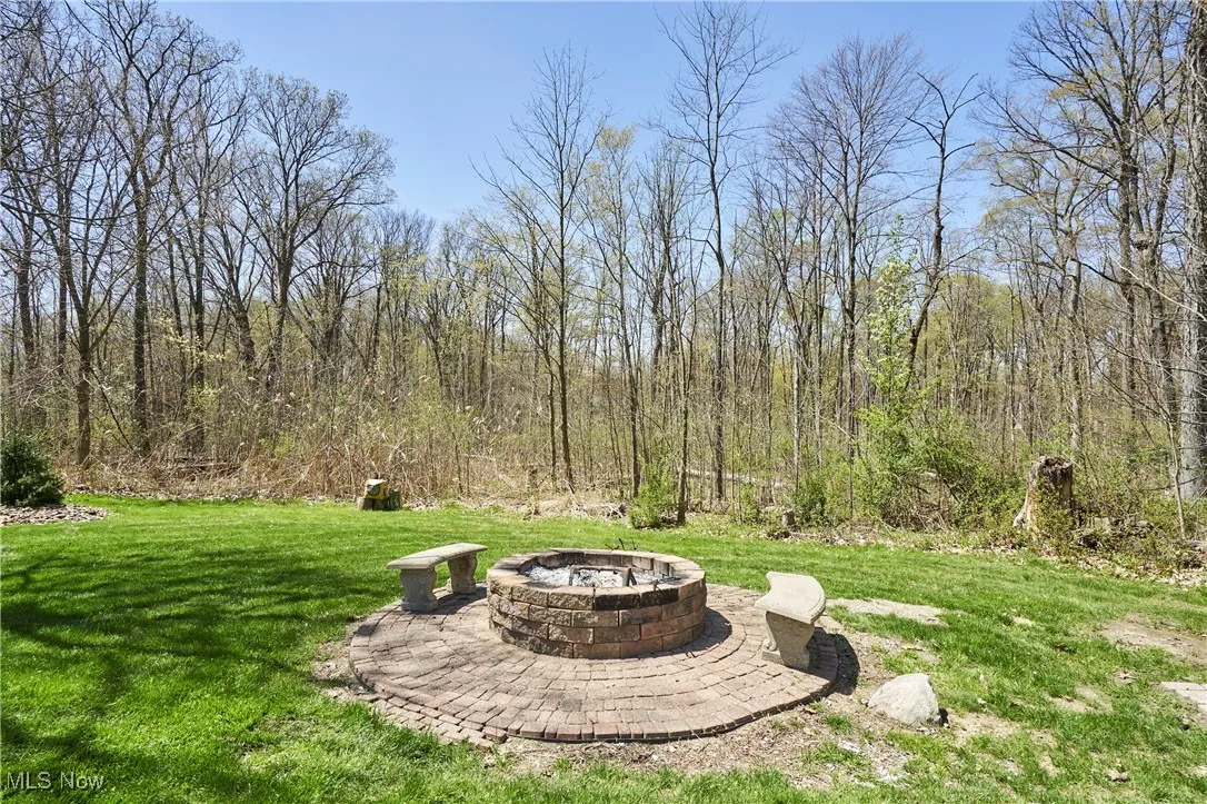 View of grassy yard featuring an outdoor fire pit