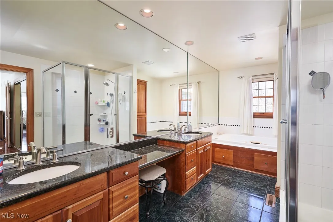Full bathroom with a stall shower, recessed lighting, vanity, and a garden tub