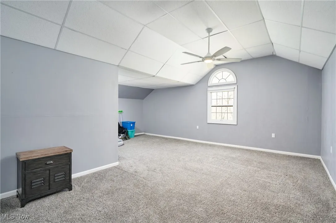 Additional living space featuring carpet floors, a ceiling fan, lofted ceiling, and baseboards