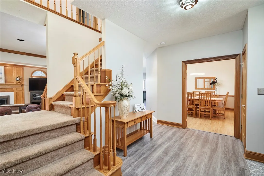 Stairs featuring wood finished floors, baseboards, a fireplace, and a textured ceiling