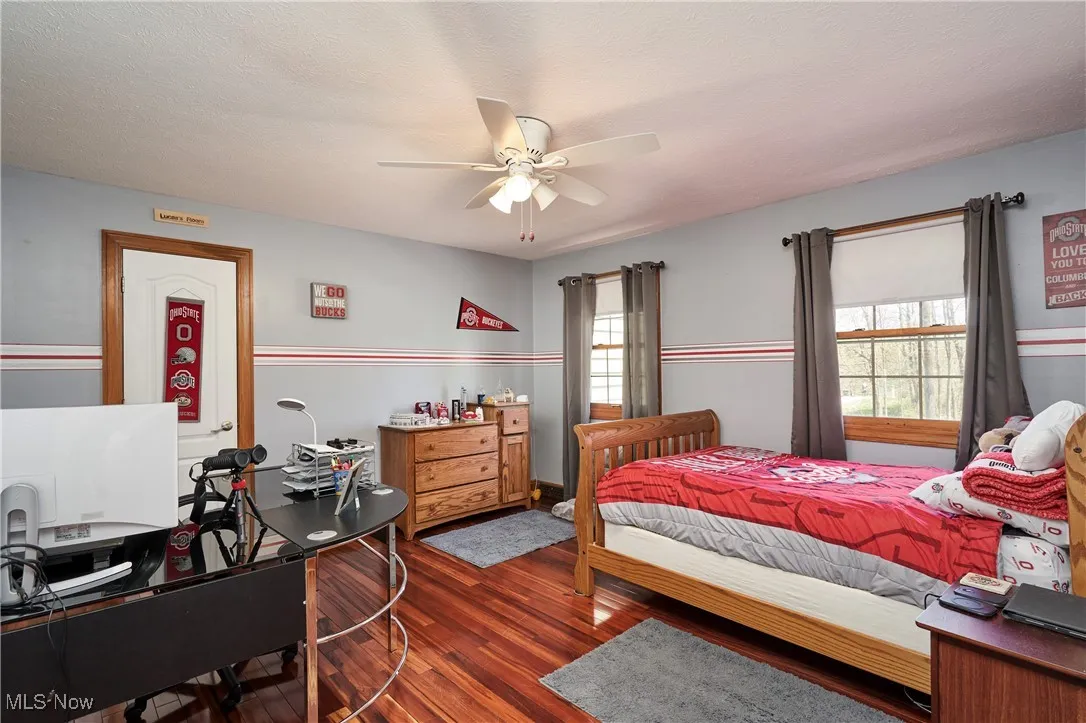 Bedroom with wood finished floors, a desk, and a ceiling fan